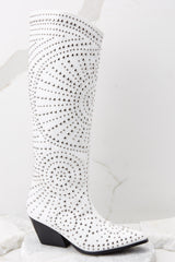 These white western-style boots feature a pointed toe, a beaded spiral design, and a soft vegan leather fabric. 