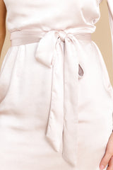 Close up view of this dress that features an asymmetrical one shoulder neckline, an adjustable self-tie at the waist, and a satin-like material.