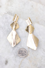 Gold earrings that feature 3 gold dangle square designs compared to quarter for actual size. Earrings measures 3.5