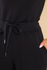 Close up view of this jumpsuit that features a stretchy waistband with a self-tie drawstring and functional pockets at the hip.