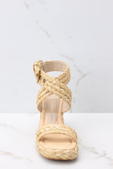 Front view of these shoes that feature an adjustable raffia-style ankle strap with a gold hardware closure, another raffia-style strap over the foot, light padding for added comfort, and an espadrille wedge style heel.