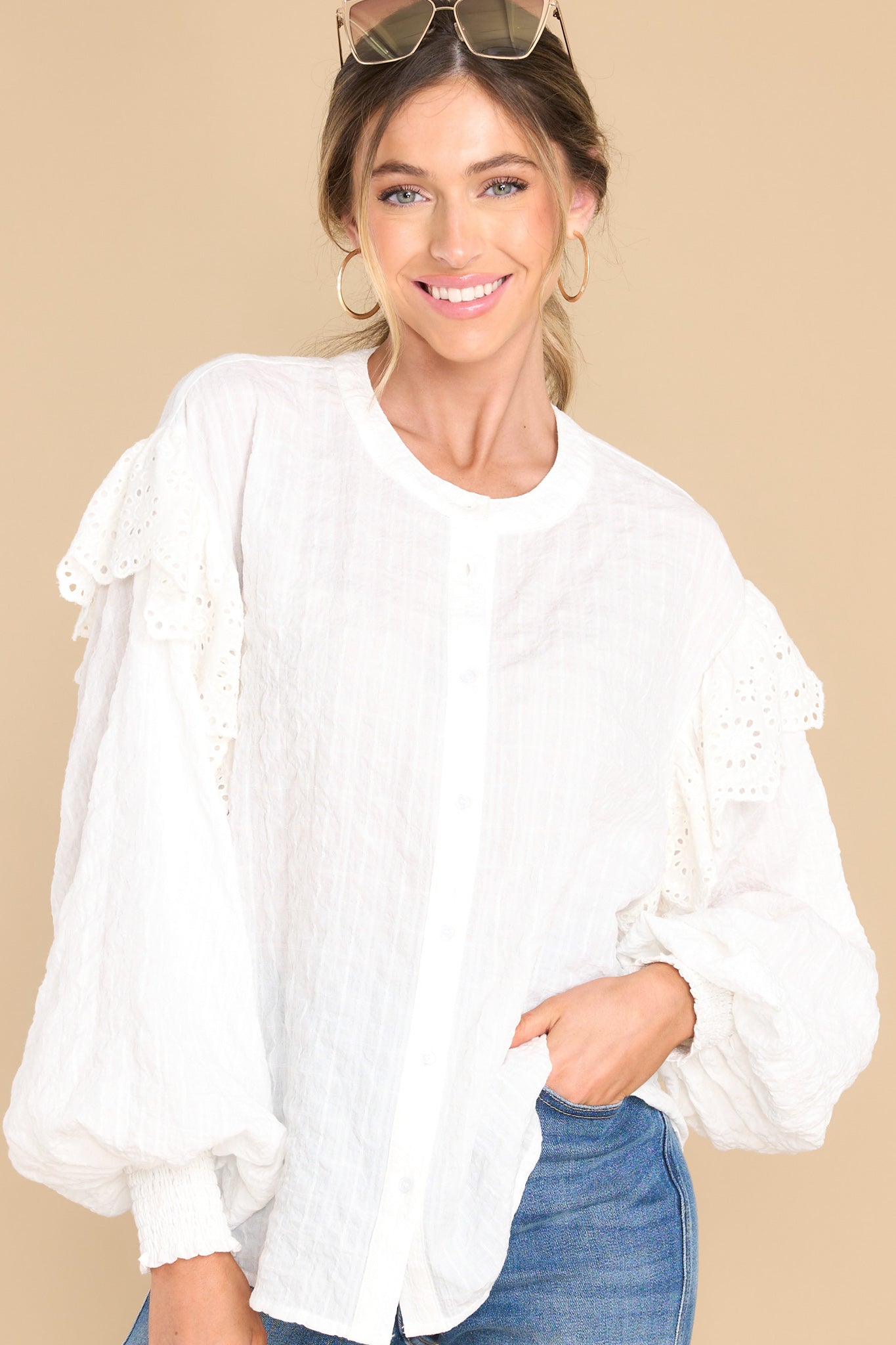 Front view of this top that features a high-neckline, buttons down the front, ruffle detail along the shoulders, puff sleeves with smock detailing at the cuffs, and a relaxed fit.