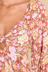 Close up view of this dress that features a v-neckline with a knot detail in the front and a small cutout below, a smocked insert at the back of the bust, half-length sleeves with elastic cuffs, and a flowy skirt.