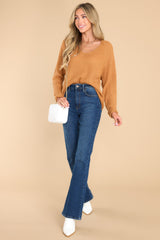 This camel colored sweater features a subtle v-neckline, long sleeves with tapered cuffs, a bottom hem that is approximately 2