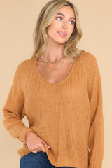 Front view of  this sweater that features a subtle v-neckline, long sleeves with tapered cuffs, and a knit texture throughout.