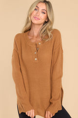 Front view of this sweater that features a round neckline with four button closures, long sleeves with tapered cuffs, slits up the sides of the bottom hem, and a waffle knit texture throughout.