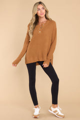 Full body view of this sweater that features a round neckline with four button closures, long sleeves with tapered cuffs, slits up the sides of the bottom hem, and a waffle knit texture throughout.