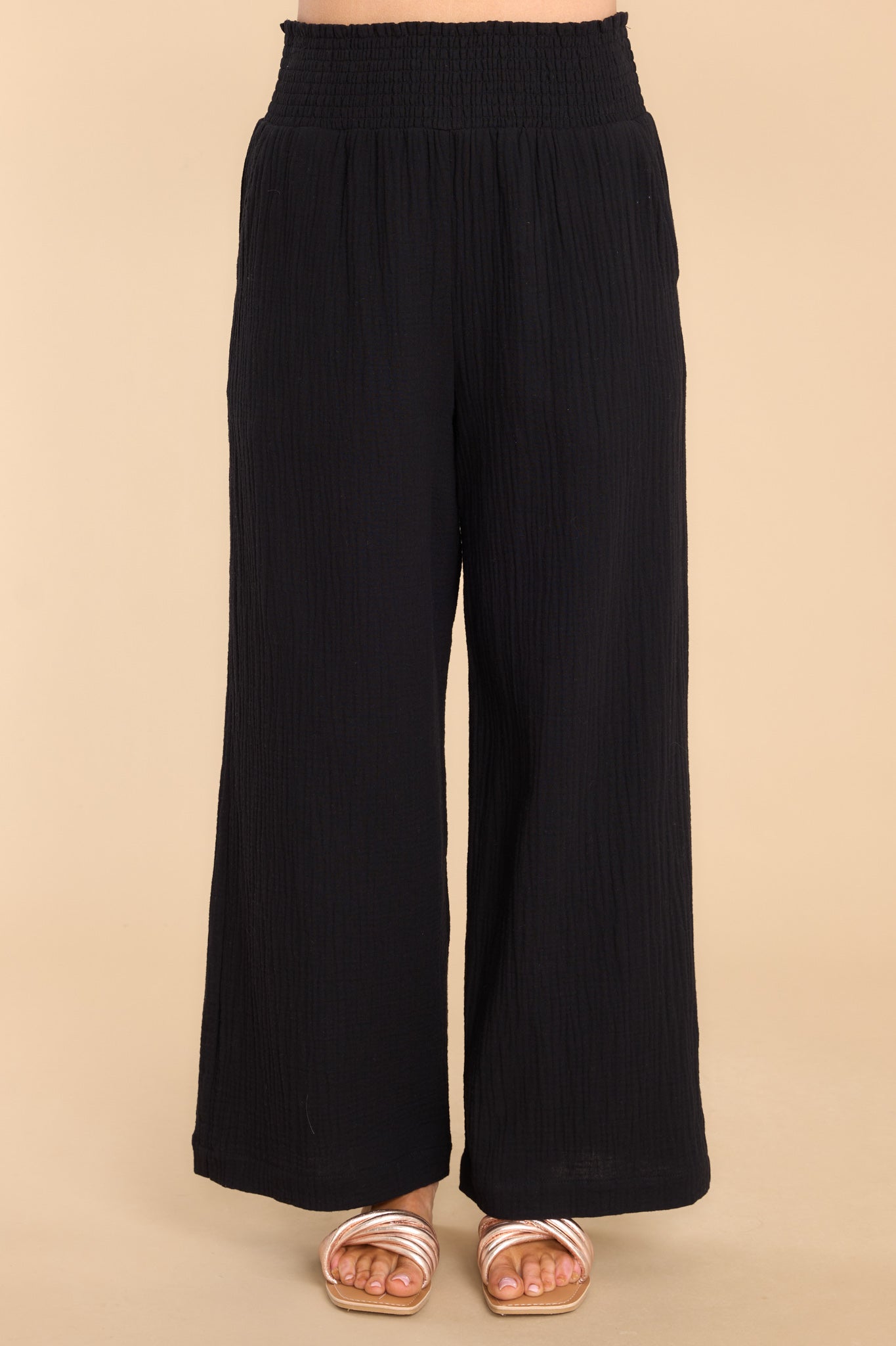 Front view of these pants that features a smock stretch waistband, pockets at the hip, and a wide flowy leg.