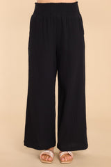 Front view of these pants that features a smock stretch waistband, pockets at the hip, and a wide flowy leg.