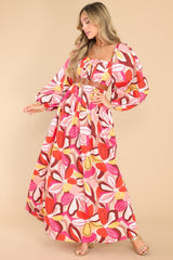 Full body view of this dress that features a square neckline, pleated detailing along the bust, long puff sleeves with elastic cuffs, a smocked section in the back of the bust, and a vibrant pattern throughout.