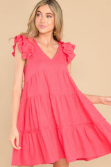 This coral colored dress features a v-neckline, flutter sleeves, a keyhole cutout at the back of the neck with a button closure, and a lightweight material throughout.