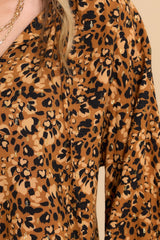 Close up view of this top that features a v-neckline with a self-tie closure, long sleeves with smocked cuffs, and gold metallic detailing throughout.