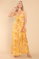 This yellow dress features a v-neckline, self-tie cutouts at the waist, thin adjustable straps, and a flowy tiered skirt.