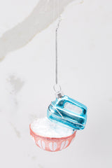Side view of this ornament that features a design of a blue mixer and a red bowl with faux silver snowflakes.