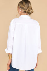 Back view of this top that features a collared neckline, long sleeves with buttoned cuffs, and a scoop bottom hem.
