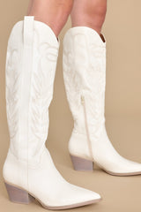 These white boots feature a pointed toe, a half-length side zipper, a faux leather finish with stitched detailing throughout, and a non-skid rubber sole.