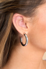 Model shown wearing hoop earrings that feature a reflective finish, silver hardware, and a secure post backing.