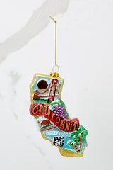 This multi-colored ornament features the shape of the state of California and highlights the Golden Gate Bridge, Hollywood, movies, and the beach.