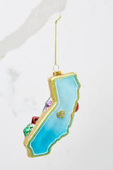 Back view of this ornament that features the shape of the state of California and highlights the Golden Gate Bridge, Hollywood, movies, and the beach.