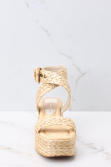 Front view of these shoes that feature an raffia style strap across the top of the foot, a raffia-style strap that wraps around the ankle with a gold hardware closure, light padding for added comfort, and an espadrille platform design.