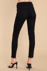 Back view of these jeans that feature a front zipper, front and back functional pockets, and a raw hemline at the ankle.