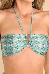 This green bikini top features a halter neckline that self-ties on the back of the neck, a silver U-shape in between the bust, removable pads, and a clasp lock on the back. 