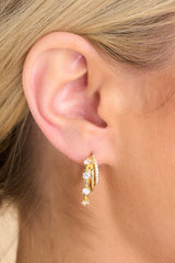 Side shot of model wearing earrings that feature encrusted rhinestones, gold hardware, 3 layered hoops, and a secure post backing. 