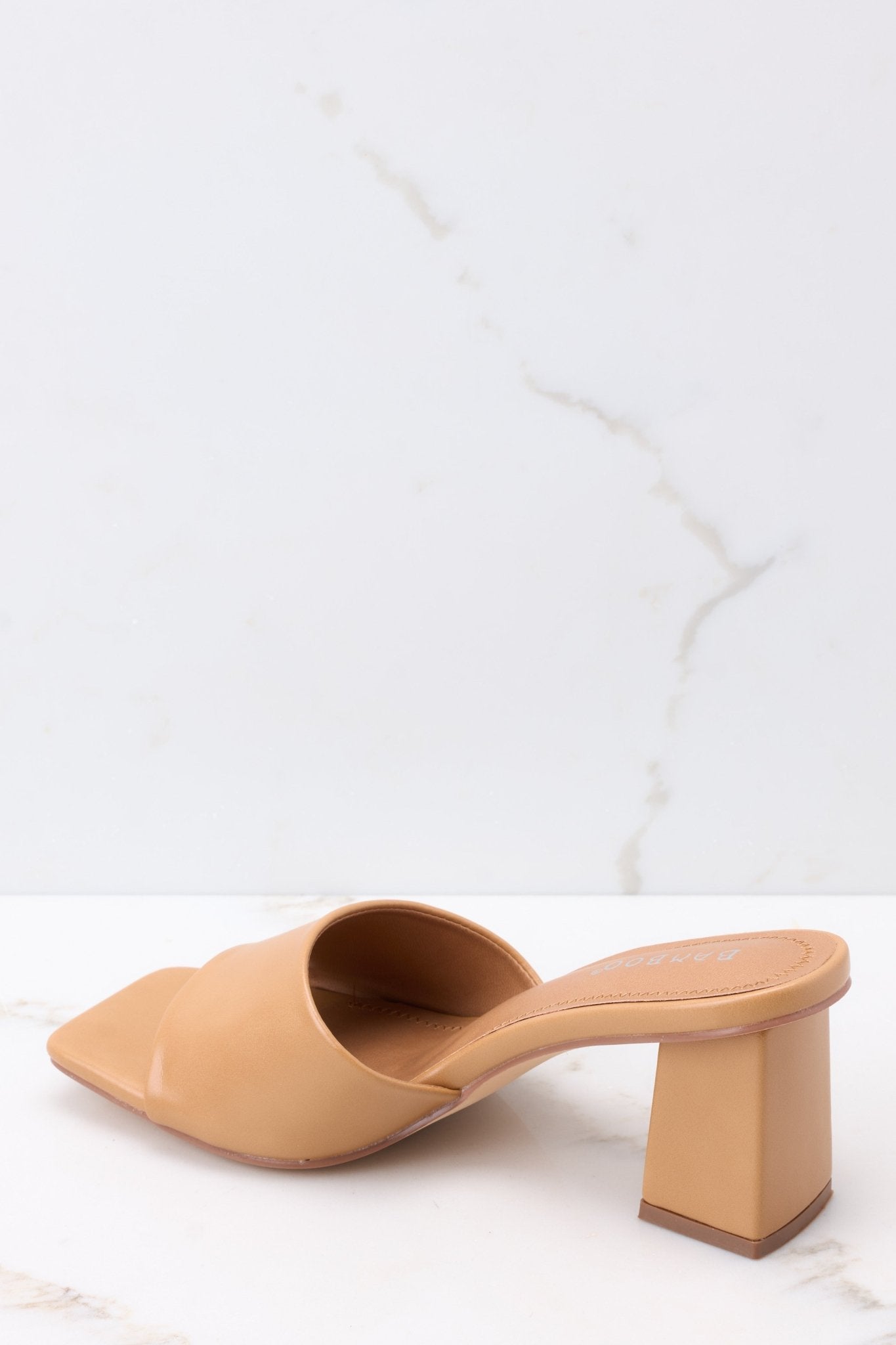 Inner-side view of these heels that feature a square toe, a thick strap across the top of the foot, a square heel, a faux-leather finish , and a slip-on design.