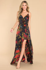 This black floral dress features a v-neckline with a snap button closure, adjustable straps, a self-tie in the back, a side zipper, ruffle detailing, and a wide slit up the leg.