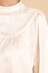 Close up view of this top that features a high neckline with buttons leading down the top of the shoulder.