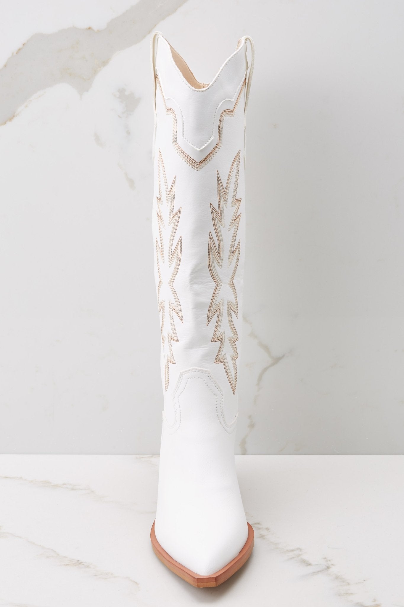 Front view of these boots that feature a pointed toe and tan stitched design up the leg.