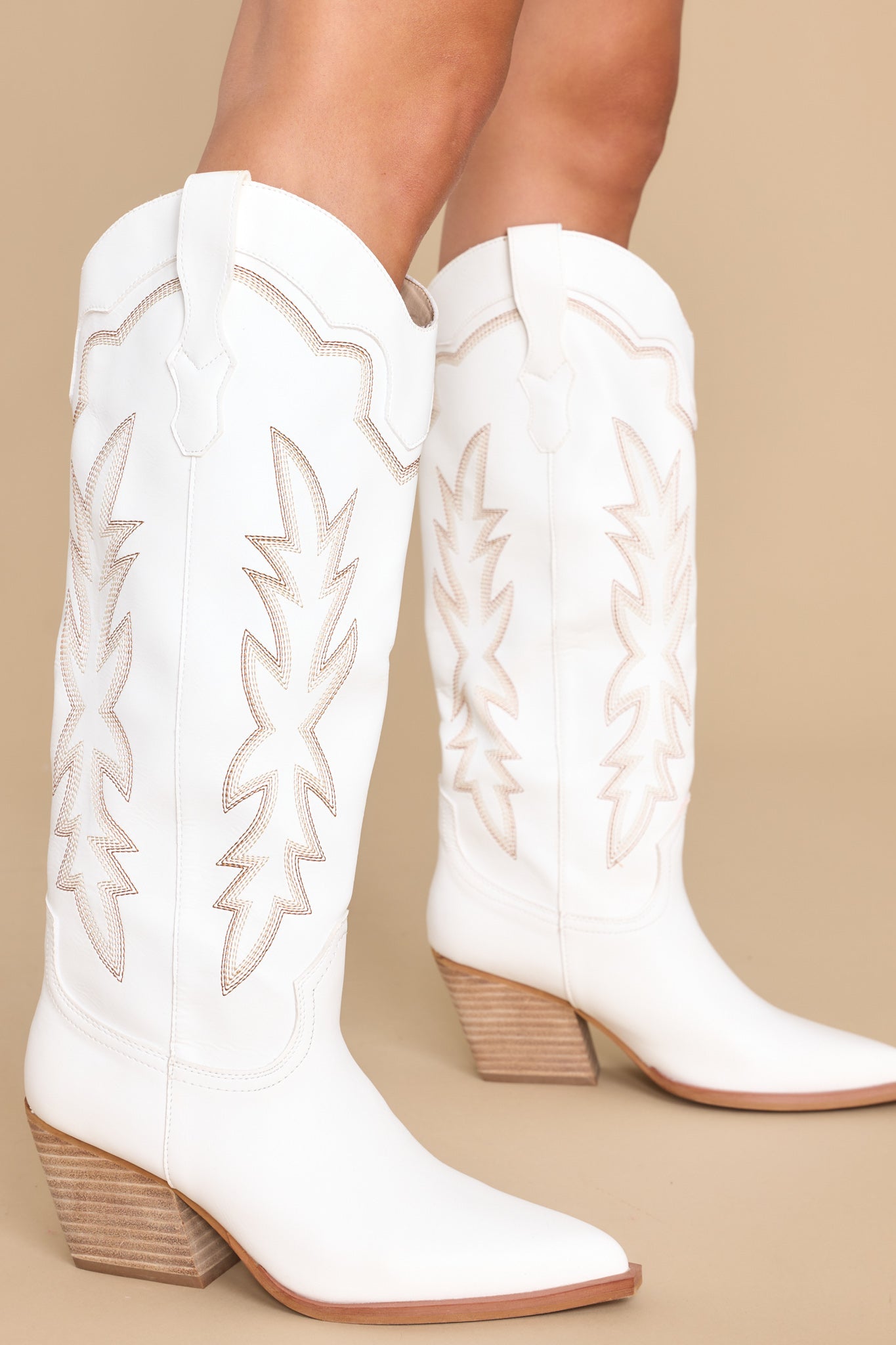These white boots feature a pointed toe and tan stitched design up the leg. 