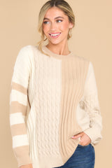 This taupe cable knit sweater features a scoop neckline, a color block design, and ribbed collar and cuffs.