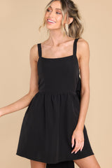 Front view of this dress that features a square neckline, adjustable shoulder straps, zipper on the side of the dress, and a non-adjustable bow detail along the back of the dress. 