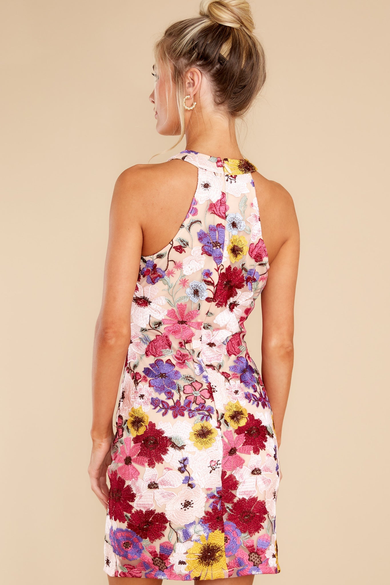 Back view of this dress that features a halter neckline, a hidden zipper down the back, and stitched flower detailing throughout.