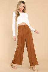 Full body view of these pants that feature a high rise, a zipper and hook and eye closure, an elastic band at the back of the waist, functional pockets, and a wide leg. 