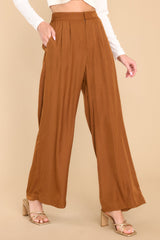 Front view of these pants that feature a high rise, a zipper and hook and eye closure, an elastic band at the back of the waist, functional pockets, and a wide leg.