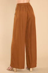 Back view of these pants that feature a high rise, a zipper and hook and eye closure, an elastic band at the back of the waist, functional pockets, and a wide leg.
