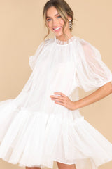 Front view of this dress that features a high ruffle collar, puff sleeves with elastic cuffs, a bottom tiered skirt, and a back keyhole opening with a button closure. 
