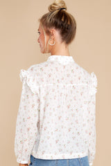 Back view of this top that features buttons and ruffles down the front and sleeves with elastic cuffs.