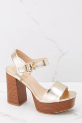 These gold shoes feature an adjustable self-tie around the ankle, thick strap over the toes, and a wooden like platform. 