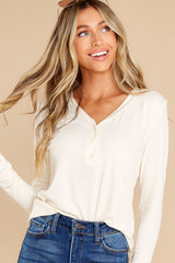 This white Henley style top features a relaxed fit with a v-neckline, long sleeves, and buttons down the bust area. 