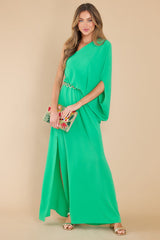 This all green dress features an off the shoulder neckline, large dolman sleeve, an elastic waistline, and an elegant side slit.