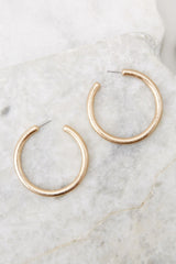 Detailed view of hoop earrings that feature a slightly matte finish, gold hardware, and a secure post backing.