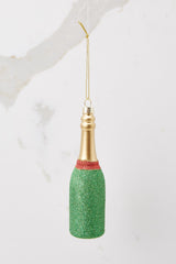 Back view of this champagne bottle ornament that features red and green glitter with gold accents and a gold string for hanging.