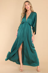 This all green dress features a plunging v-neckline, dolman sleeves, an elastic waistband, a flowy skirt with a slit up the center, and a lining that extends from the waist to the thigh.