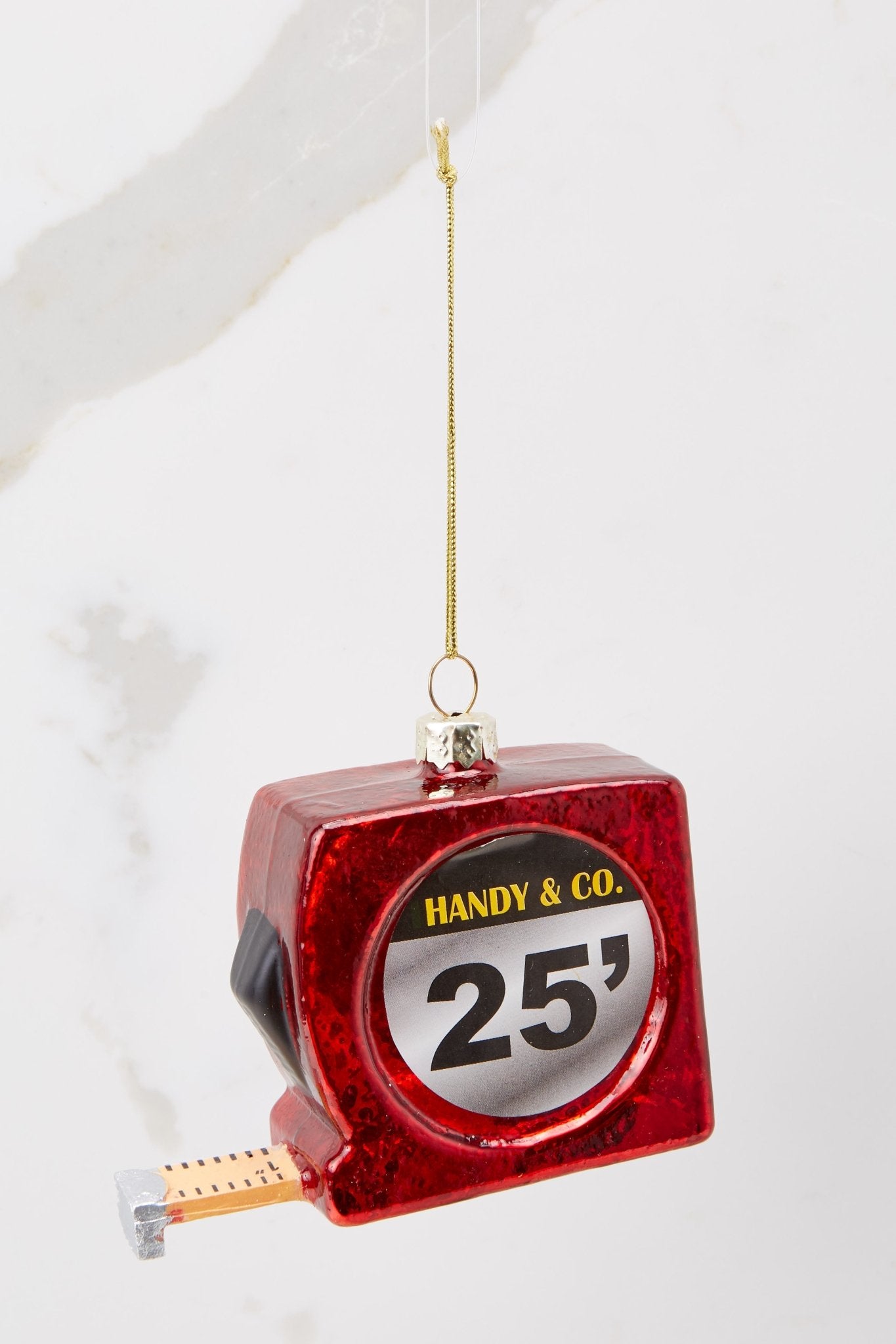 Front view of this ornament that features a red measuring tape with a gold string to hang on the tree