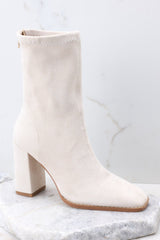 Outside view of ivory booties featuring a square toe, and a block heel. 