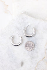 Size comparison shot of worn silver hoops next to a quarter.