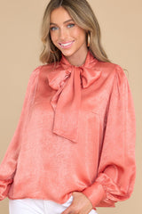 Front view of this top that features a high neckline with an adjustable self tie, flowy balloon sleeves with two buttons at the cuff, and a relaxed fit.